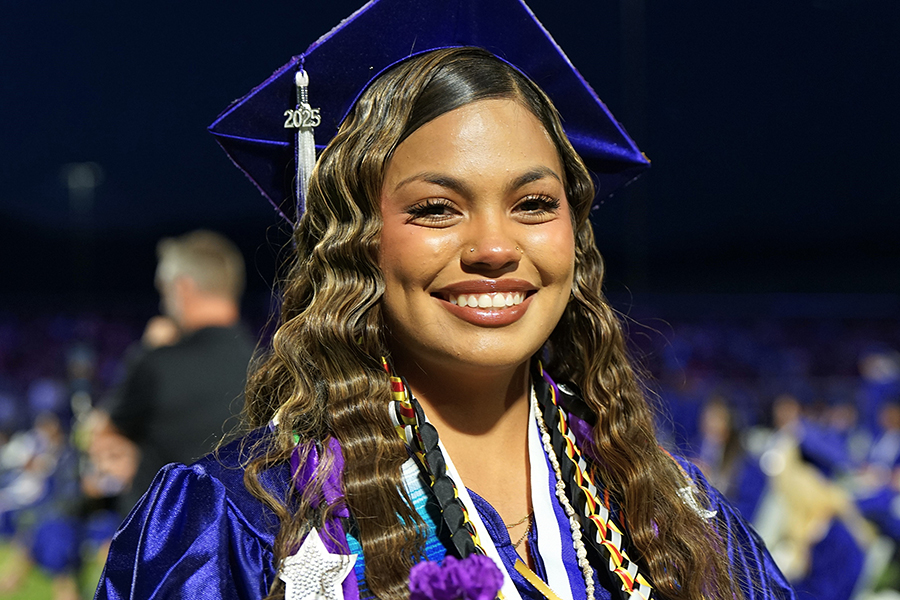 A graduate smiles proudly as she walks across the field