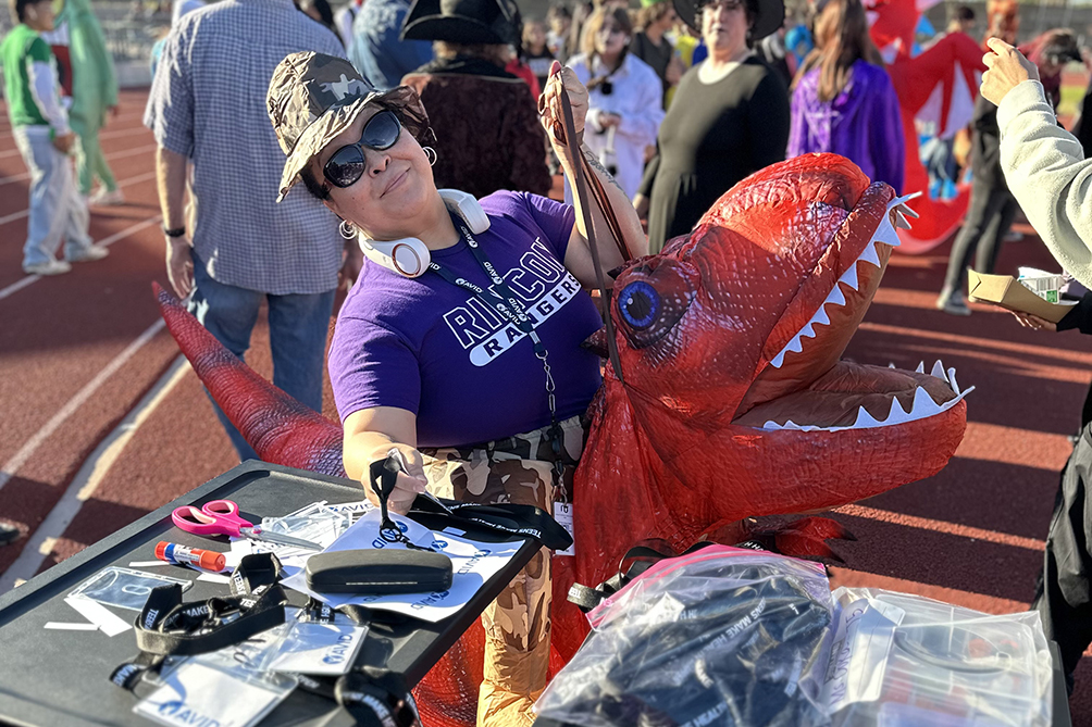 A woman in a purple shirt and inflatable red dinosaur costume