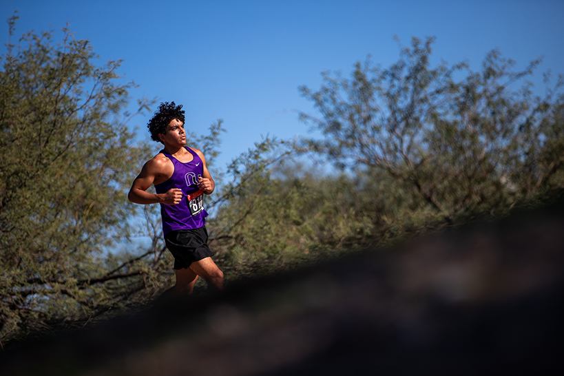 A teen boy runs up a hill