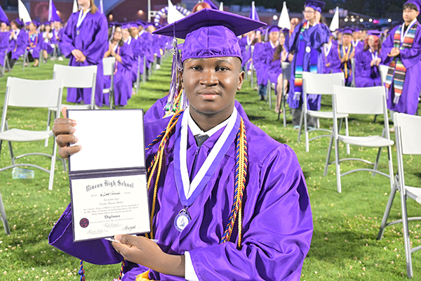 A graduate proudly holds up his diploma