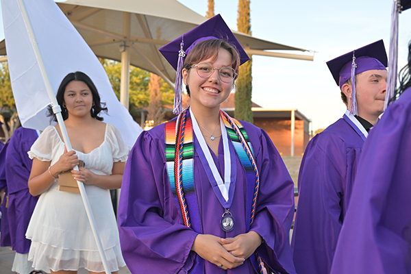 A teen girl smiles as she walks into the stadium for the graduation ceremony