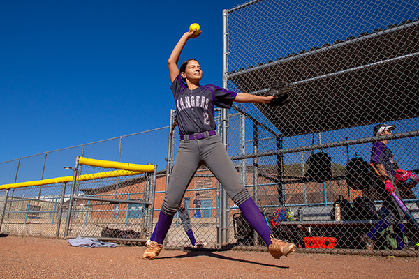 A girl swings her arm as she warms up to pitch the softball