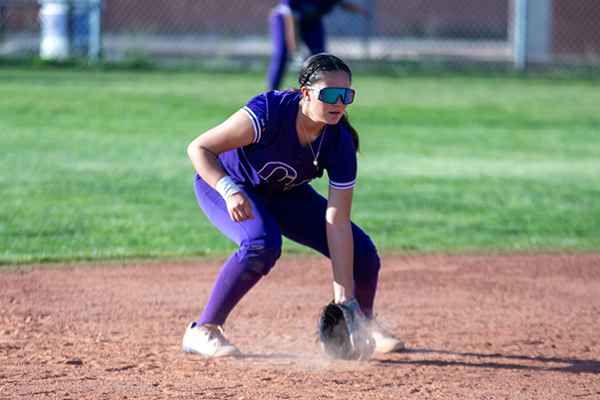 A girl puts her mitt on the ground to catch the softball