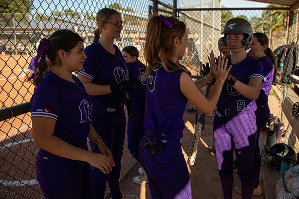 The girls team high-fives each other in the dugout