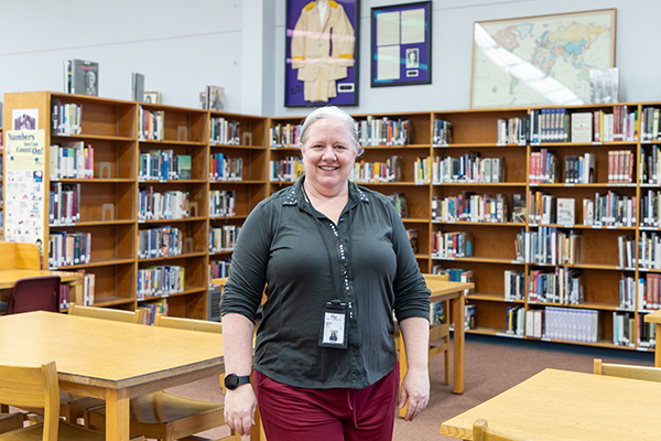 A woman smiles in front of shelves of books