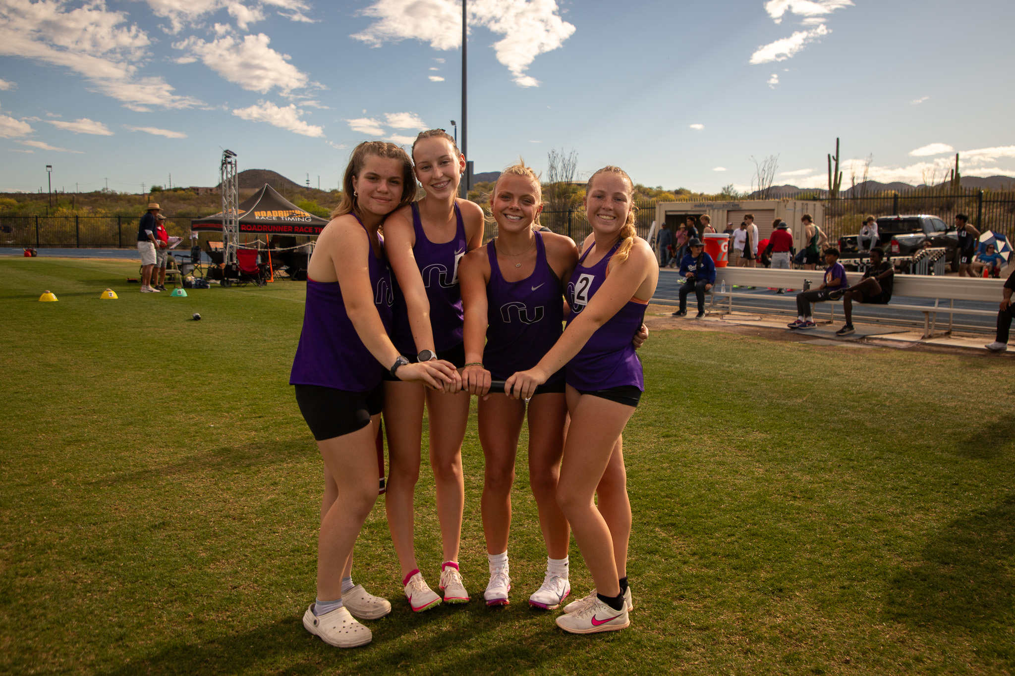 Four girls from the RUHS track team pose for a photo on the field