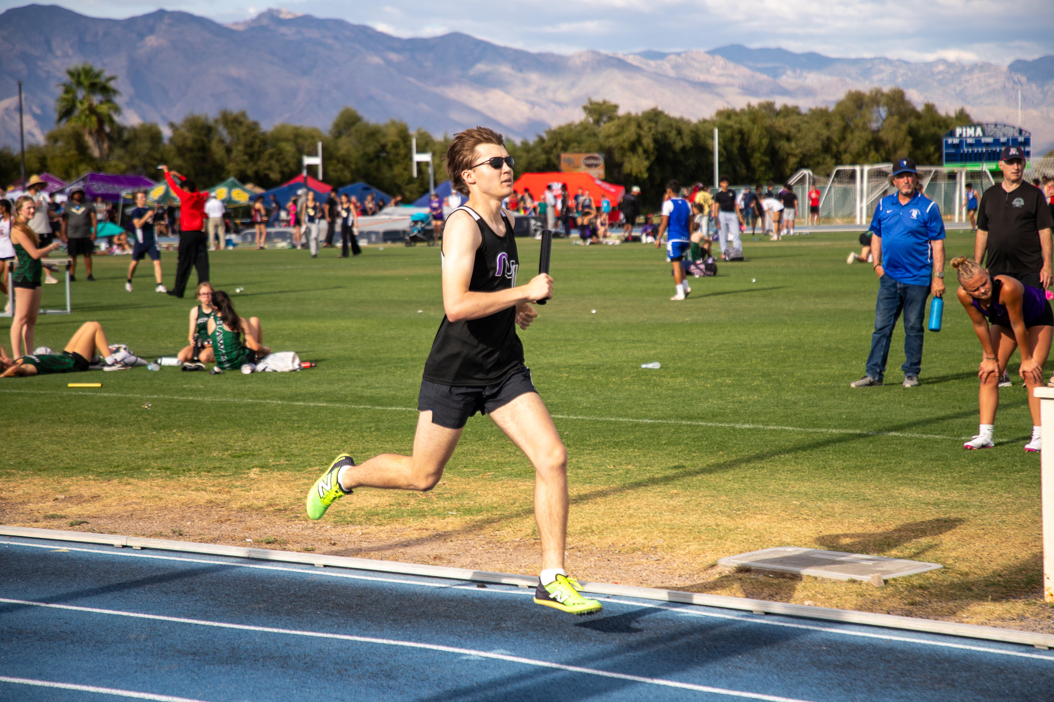 A boy runs on the track holding a baton during the relay