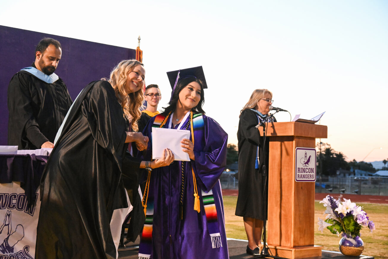 A Rincon grad poses with her diploma while shaking the principal's hand